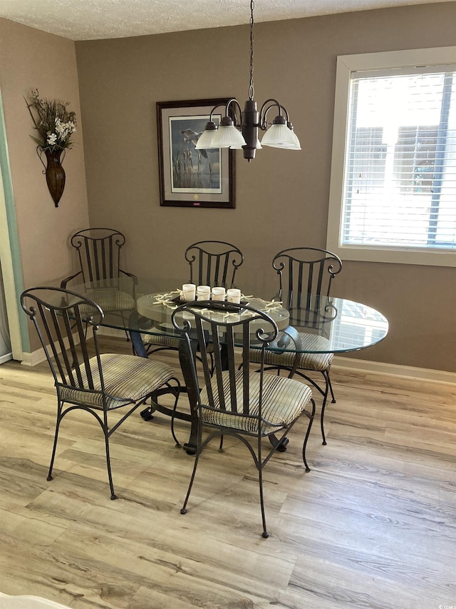 dining area featuring a notable chandelier, a textured ceiling, and light hardwood / wood-style flooring