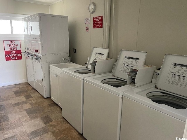 clothes washing area featuring cabinets, stacked washer and dryer, and washing machine and clothes dryer