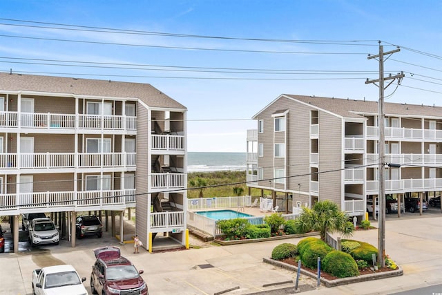 view of property featuring a water view, a carport, and a community pool