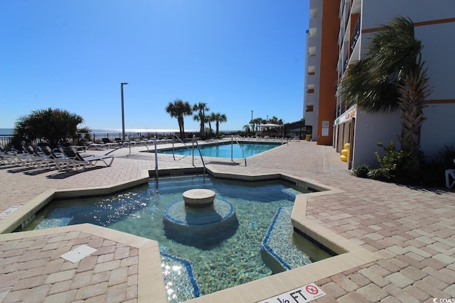 view of pool with a patio and a community hot tub