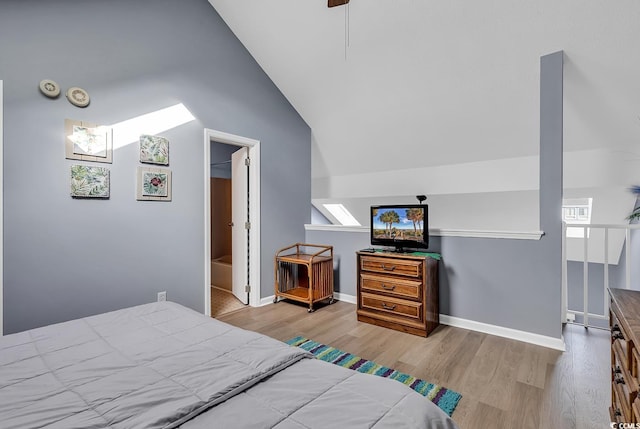 bedroom featuring vaulted ceiling, light hardwood / wood-style floors, ceiling fan, and ensuite bath