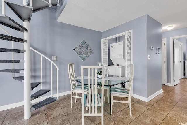 dining room featuring a textured ceiling, light tile floors, and stacked washing maching and dryer