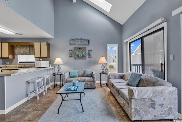 living room with a skylight, tile flooring, and high vaulted ceiling