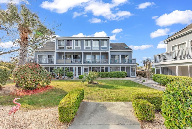 back of property featuring a balcony and a lawn