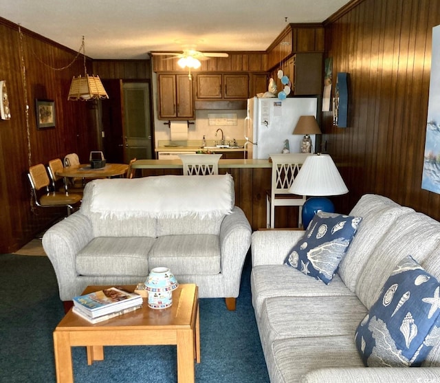 living room featuring ceiling fan, carpet flooring, ornamental molding, and wood walls