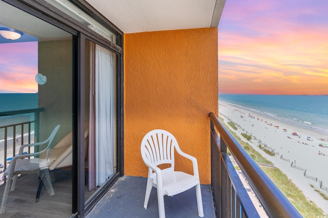 balcony at dusk with a beach view and a water view