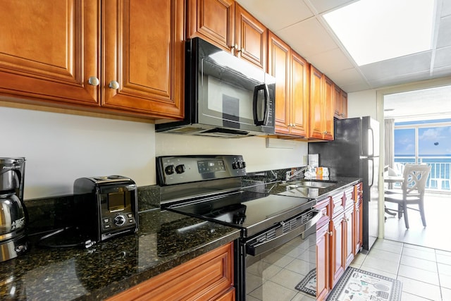 kitchen featuring light tile floors, electric stove, dark stone countertops, a drop ceiling, and sink