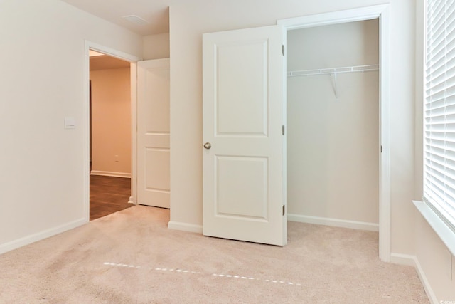 unfurnished bedroom with a closet and light colored carpet