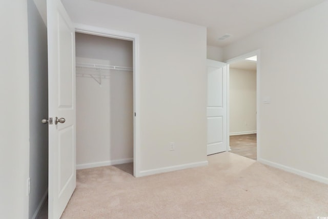 unfurnished bedroom with light carpet and a closet