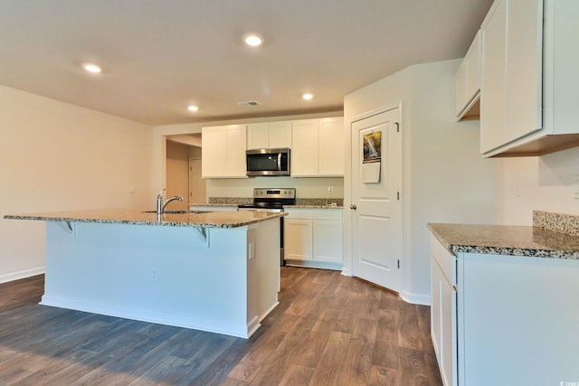 kitchen with stainless steel appliances, dark wood-type flooring, and dark stone counters