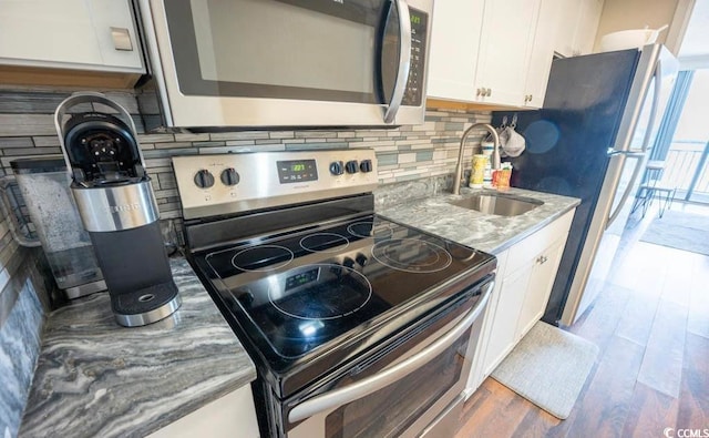 kitchen with white cabinetry, sink, stainless steel appliances, and hardwood / wood-style floors