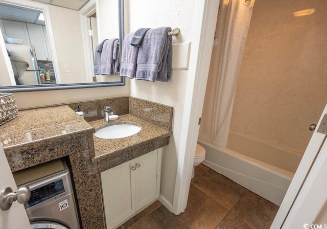 full bathroom with toilet, bathing tub / shower combination, vanity, washer / clothes dryer, and tile flooring