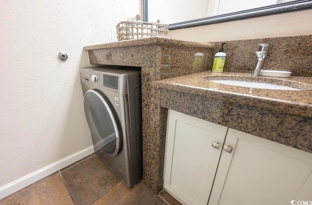 washroom with sink, washer / clothes dryer, and dark tile floors