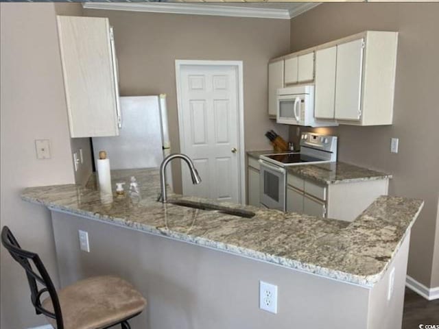 kitchen with white cabinets, white appliances, and kitchen peninsula