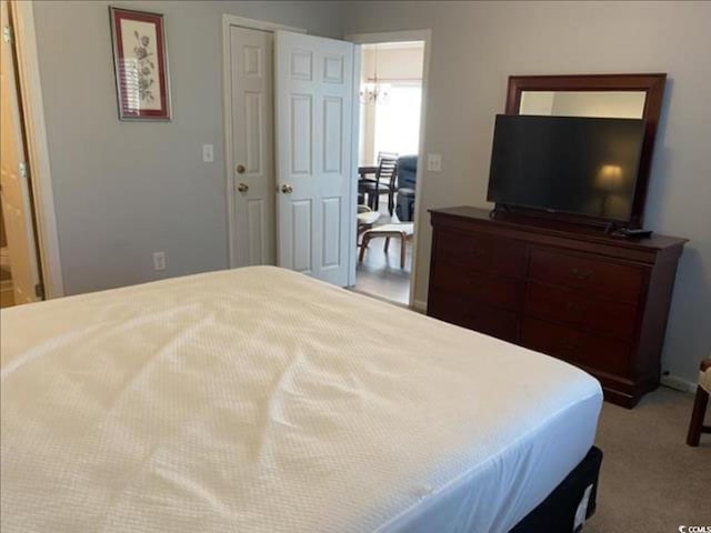 bedroom featuring light colored carpet and a chandelier