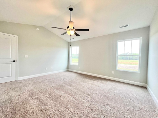 carpeted spare room featuring a wealth of natural light, vaulted ceiling, and ceiling fan