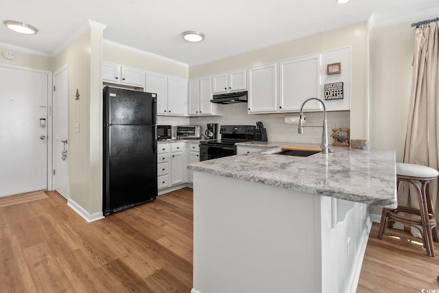 kitchen with a kitchen bar, kitchen peninsula, white cabinetry, light hardwood / wood-style flooring, and black appliances