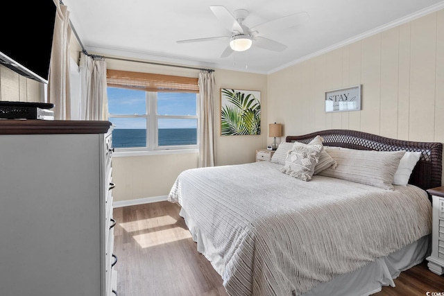 bedroom featuring ceiling fan, a water view, ornamental molding, and wood-type flooring