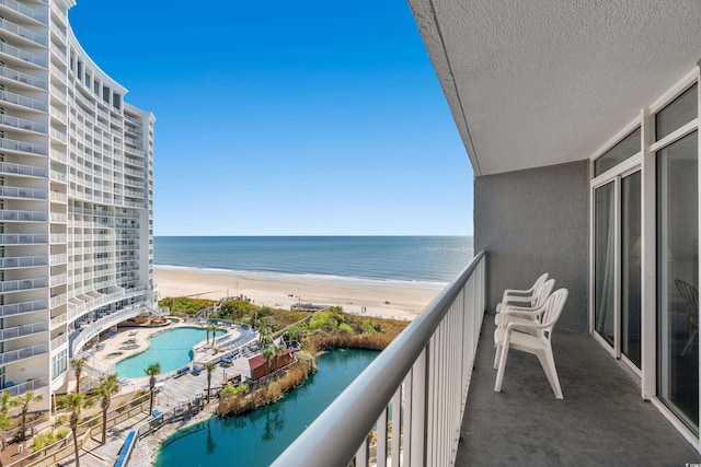 balcony featuring a beach view, a community pool, and a water view