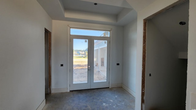 entryway featuring french doors, concrete flooring, and a tray ceiling