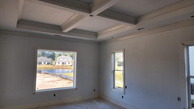 empty room featuring a water view, beam ceiling, and plenty of natural light