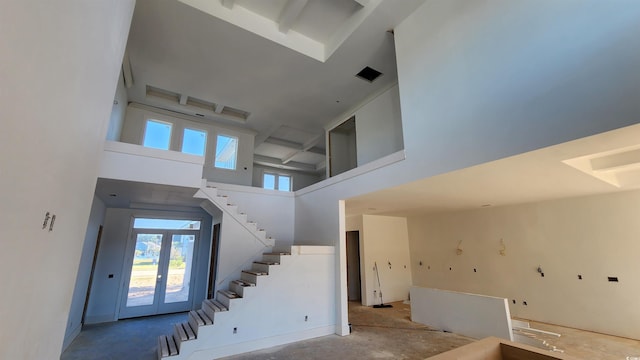 staircase with french doors, concrete floors, a high ceiling, and a wealth of natural light