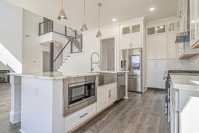 kitchen featuring a center island with sink, white cabinetry, sink, decorative light fixtures, and stainless steel appliances