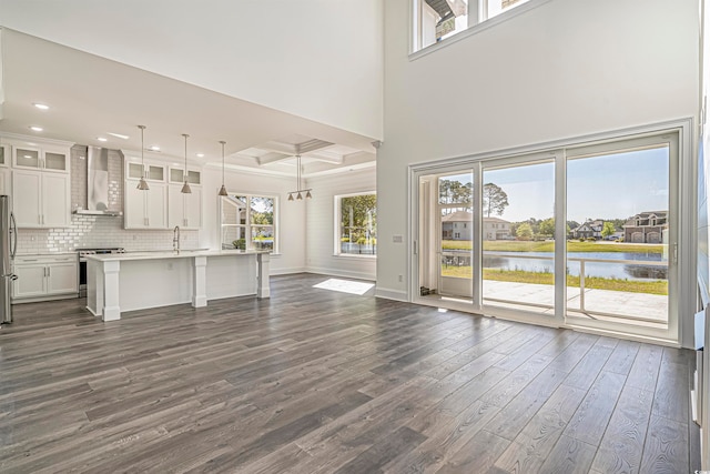 unfurnished living room with a water view, dark wood-type flooring, a wealth of natural light, and sink