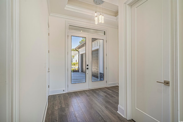 entryway with french doors, a tray ceiling, dark wood-type flooring, ornamental molding, and an inviting chandelier