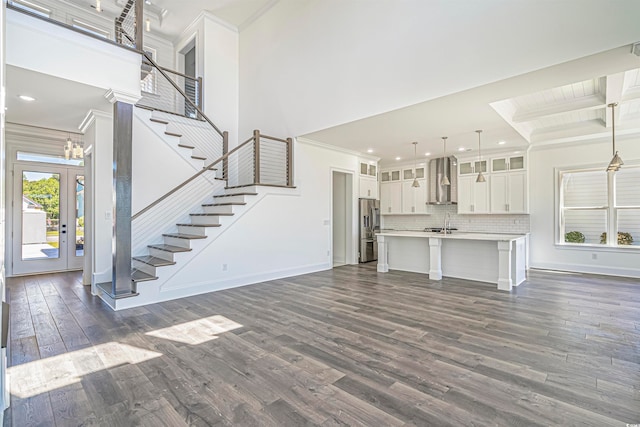 unfurnished living room with ornamental molding, sink, a high ceiling, and dark hardwood / wood-style flooring