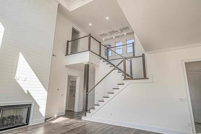 unfurnished living room with a fireplace, ornamental molding, dark wood-type flooring, and a high ceiling