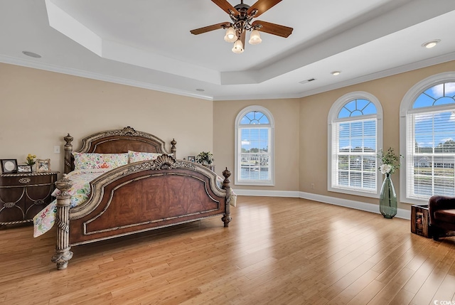 bedroom featuring light hardwood / wood-style floors, ceiling fan, and a tray ceiling