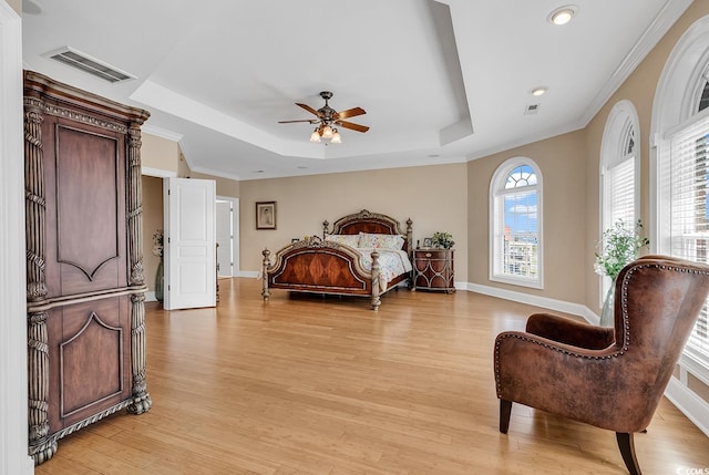 bedroom featuring crown molding, light hardwood / wood-style floors, ceiling fan, and a tray ceiling