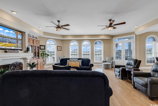 living room featuring ceiling fan, light hardwood / wood-style flooring, a wealth of natural light, and french doors