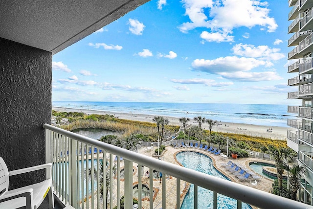 balcony featuring a view of the beach, a water view, and a community hot tub