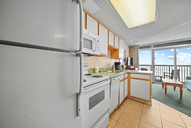 kitchen featuring light tile patterned floors, sink, white appliances, a textured ceiling, and white cabinetry