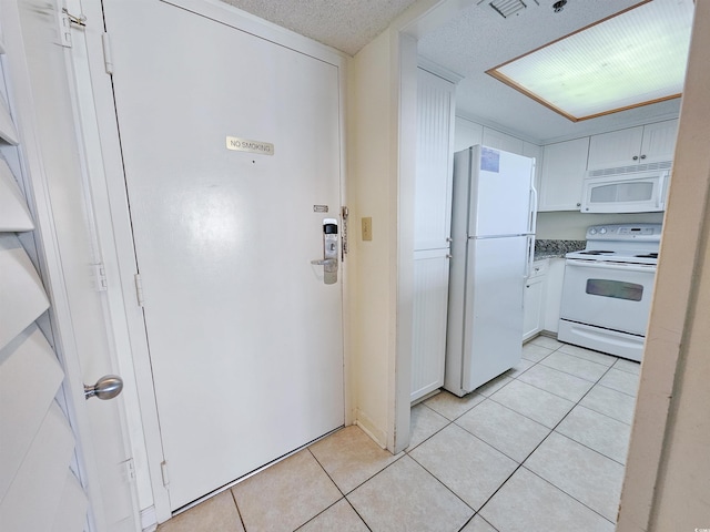 kitchen with white cabinets, white appliances, a textured ceiling, and light tile flooring