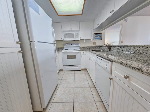 kitchen featuring light tile floors, white cabinets, sink, white appliances, and light stone countertops