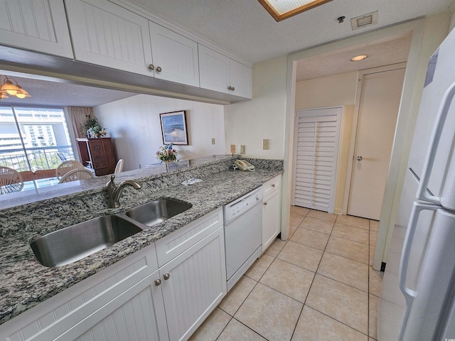 kitchen with light tile floors, white cabinets, sink, white appliances, and stone counters