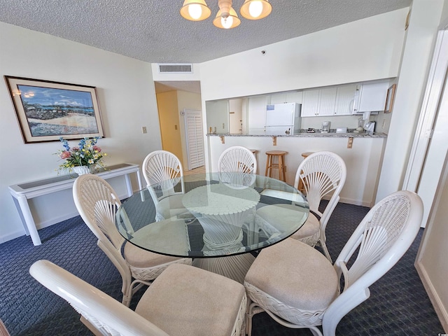 dining area featuring a notable chandelier, carpet floors, and a textured ceiling