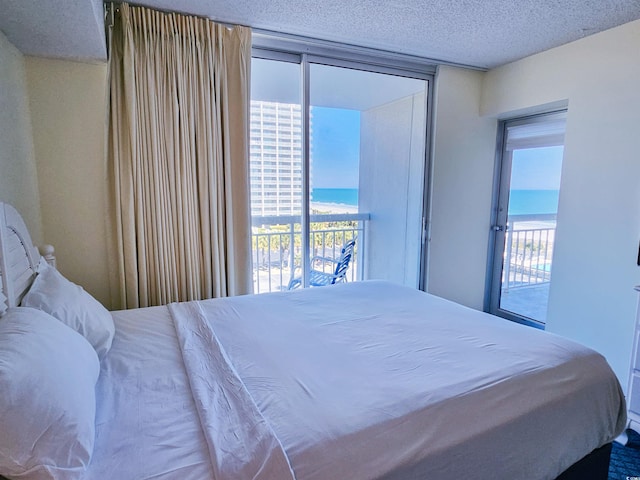 bedroom featuring a water view, access to exterior, and a textured ceiling