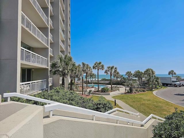 view of home's community featuring a water view, a swimming pool, and a lawn