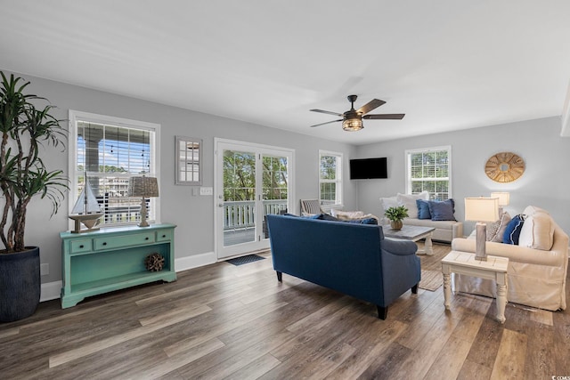 living room with dark hardwood / wood-style flooring, ceiling fan, and a healthy amount of sunlight