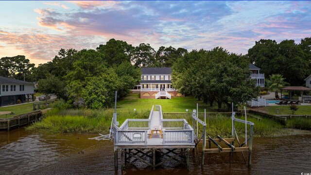 view of dock featuring a swimming pool, a yard, and a water view