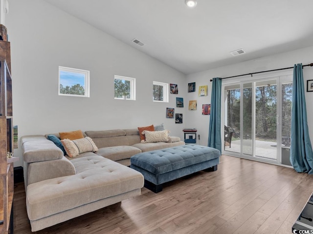 living room featuring high vaulted ceiling, light hardwood / wood-style flooring, and a healthy amount of sunlight