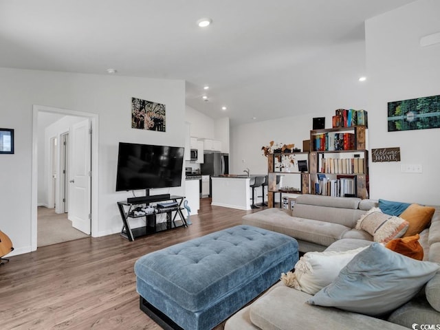 living room featuring high vaulted ceiling and light hardwood / wood-style flooring