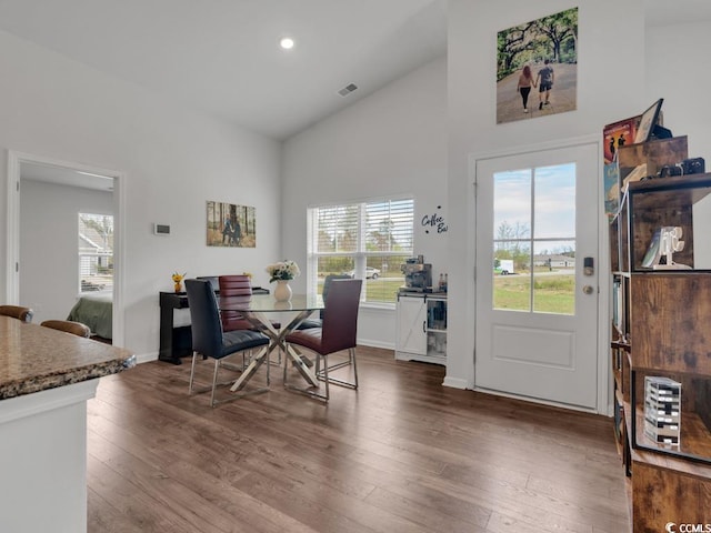 dining space with dark hardwood / wood-style floors and high vaulted ceiling