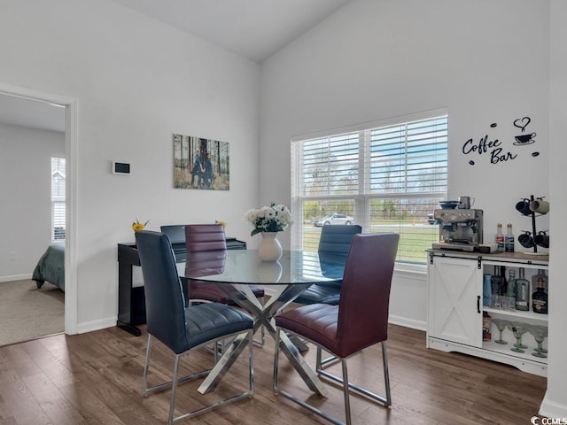 dining space with high vaulted ceiling and dark carpet