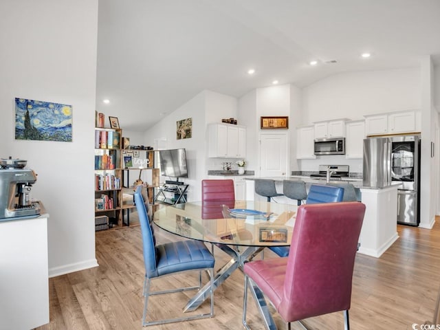 dining area with high vaulted ceiling and light wood-type flooring