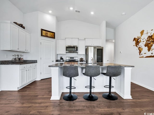 kitchen featuring appliances with stainless steel finishes, dark hardwood / wood-style flooring, white cabinetry, and an island with sink